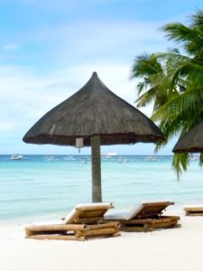 Traumstrand mit Kokospalme, Sonnenschirm und Liegestühlen